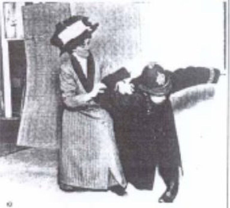 Kampfsportlerin Edith Garrud demonstriert einen Jujitsu-Wurf an einer Frau in langem edwardianischem Kleid.